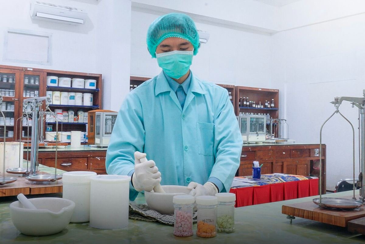 Pharmaceutical technician in protective clothing preparing samples